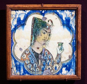Ceramic tile depicting young woman holding vase by Persian School