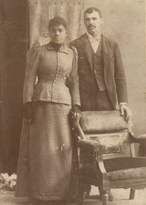 Photograph of an African-American couple standing behind a chair by Schmitz Studio