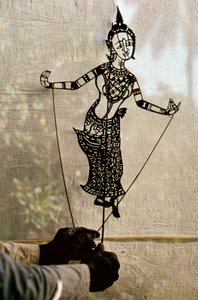 Puppeteer Manipulates Storytelling Shadow Puppet Against a Scrim for a Shadow Play