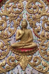 Entrance door ornamented with gold reliefs. The Teaching Buddha depicts a particular moment in the life of the Buddha, namely, the first sermon the Buddha gave after reaching Enlightenment, Vang Vieng, Laos