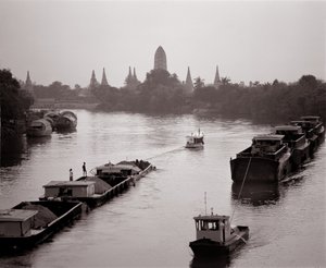 River barges on Chao Phraya River with a view of Wat Chaiwatthanaram