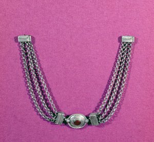 Silver necklace comprising a cornelian, in an oval setting edged with a cable moulding, suspended between two lengths of three chains fastened by a box-like clasp, found in Great Chesters, mid 1st to early 2nd century AD