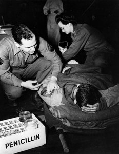 Second World War: Luxembourg February 1945: In a US Army evacuation hospital, a medic (nurse) administers penicillin to an injured soldier to avoid infection while a nurse prepares him for an operation