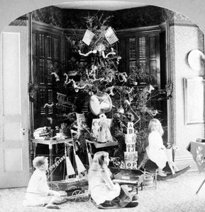 Children gathered at the foot of the tree surrounded by gifts on Christmas morning