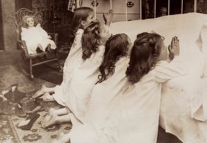 Four little girls kneeling at the side of a bed as they say their evening prayer