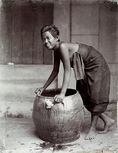 Young smiling Thai woman, pushing a large container by Unknown photographer