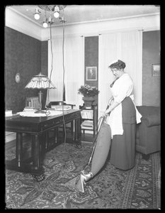 Unidentified woman demonstrating the use of the Apex vacuum cleaner, c.1913-14