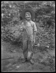 William Gray Hassler in straw hat and overalls, carrying fishing pole and basket in the woods by William Davis Hassler