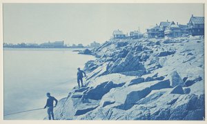 Two Men Fishing from Rocks at Seaside Resort