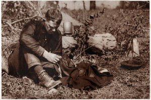 Tramp repairing his clothes by . .