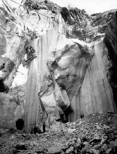 Excavators at work along a steep wall of a marble quarry in the Apuan Alps, Tuscany by A. Corsini