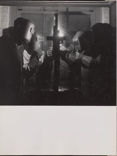 Four men wearing welding helmets welding a piece of metal by Arnold Eagle