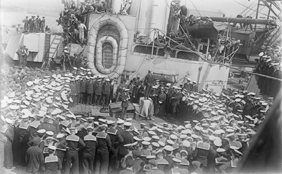 Seamen crowd around Australian Prime Minister William Morris (Billy) Hughes as he addresses them on the deck of HMAS Australia at the dockyard in Devon, England, 21 May 1916 by Australian Photographer