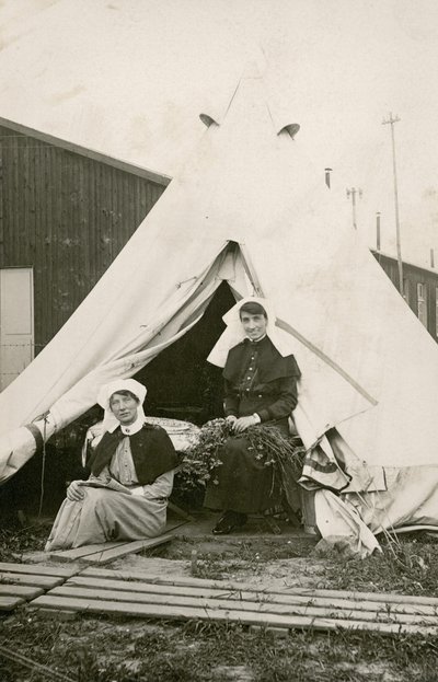 Sister Eleanor Wibmer Jeffries and Sister Nellie Constance Morrice outside their tent at No 3 Australian General Hospital with flowers picked from the bank of the Somme, c. June 1917 by Australian Photographer