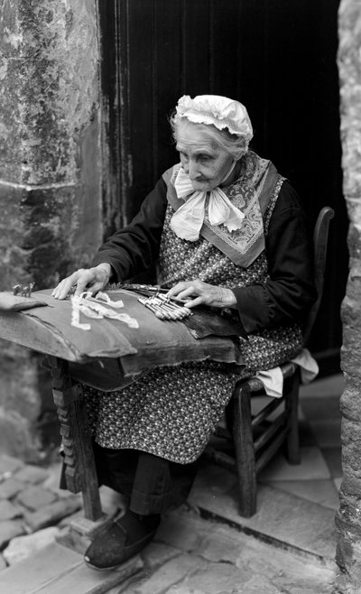 Lacemaker, an elder woman, in Bruges is seated at her doorway while making lace by B. Anthony Stewart
