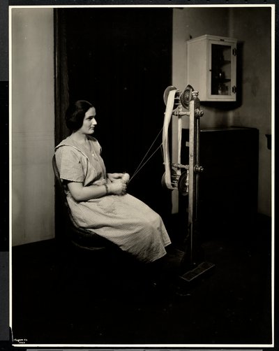 Portrait of a blind, deaf and dumb young woman spinning wool at the New York Association for the Blind, 111 East 59th St., New York by Byron Company
