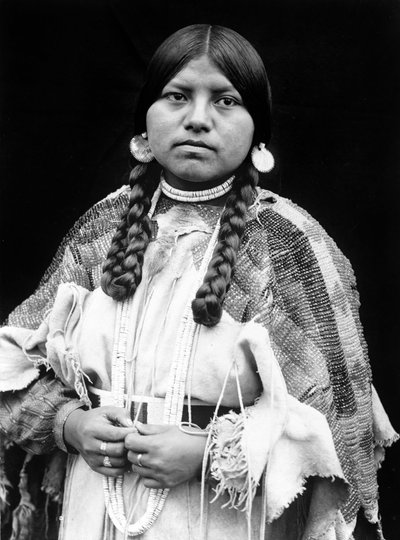 Cayuse woman, half-length portrait, standing, facing front, braids, shell disk earrings, shell bead choker and shell beads around neck, beaded buckskin dress with beaded belt c. 1910, photo Edward S. Curtis by Edward Sheriff Curtis