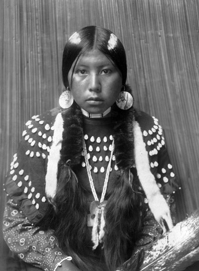Kalispel Indian woman, white stripes painted on hair, shell disk earrings, wearing blanket dress decorated with elks