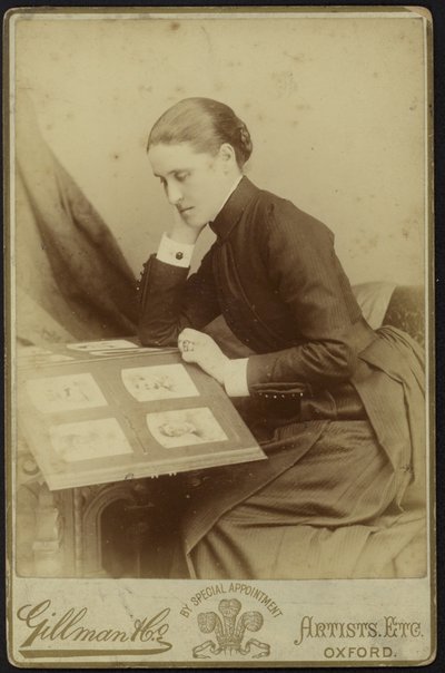 Figure of a woman sitting inspecting a photograph album by English Photographer
