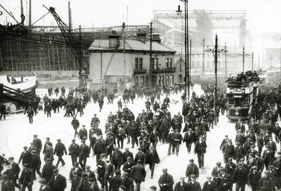 Knocking-off time at the Harland and Wolff shipyard, Belfast, Ireland with the Titanic under construction in the background, 1910-11 by English Photographer