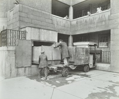 Ossulston Estate: dustmen empty container at the bottom of the rubbish chute by English Photographer