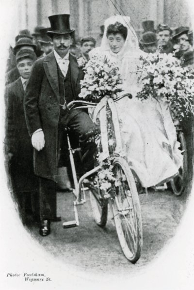 Roman Catholic couple leaving Notre Dame de France, Leicester Square, on bicycles by English Photographer