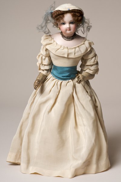 Bisque fashion doll with swivel head, wearing a long cream dress and hat by English School
