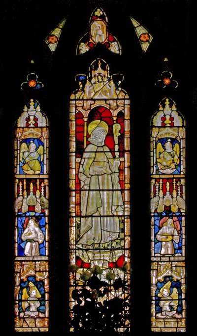 The East window depicting musician angels surrounding the central figure of a sainted bishop by English School