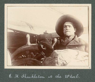 E H Shackleton standing by wheel of the 