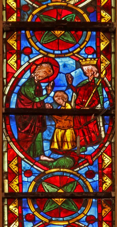 Window w213 depicting a scene from the life of St Thomas: the saint at a marriage banquet for the daughter of the king of India has his face slapped by a cupbearer; a lion removes his arm by French School