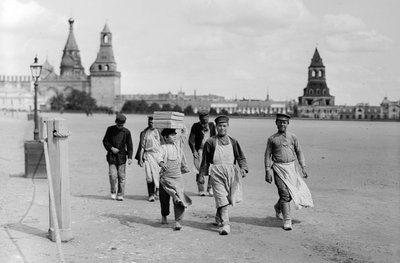 Russian Muscovite workmen march to work with battlements of the Kremlin fortress in background by Gilbert H. Grosvenor