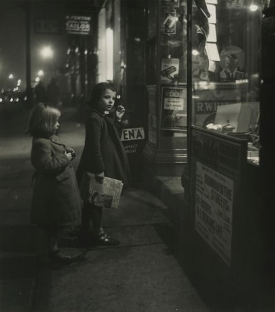 Two Little Girls in Winter Coats Standing Outside a Shop at Night by Godfrey Macdominic