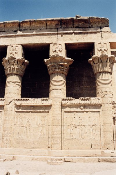 The south wall of the Roman Birth House, or Mammisi, with reliefs depicting a pharaoh making offerings to gods and columns topped with images of Bes by Greco Roman