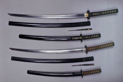 Top: a katana, Japanese sword and its sheath, wakizashi, Japanese short sword in its sheath, small Kokatawa dagger stows in the same scabbard. All three are from the 18th century. The lower ones are from the 17th century by Japanese School