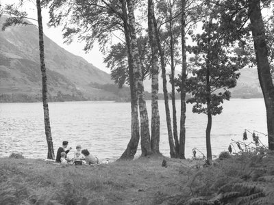 A family relaxing near to lake with trees to right and hills in background by Joseph Hardman