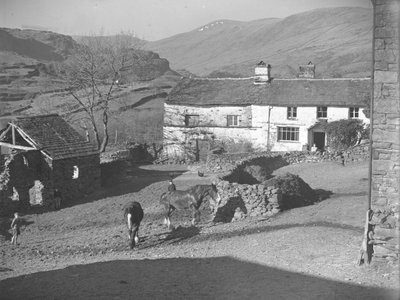 Three young boys watching horses in farmyard at Kentmere with farmhouse and hills behind by Joseph Hardman