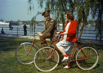 Sitting on bicycles near a harbor, US Army officer flirts with a young woman on Trinidad by Luis Marden