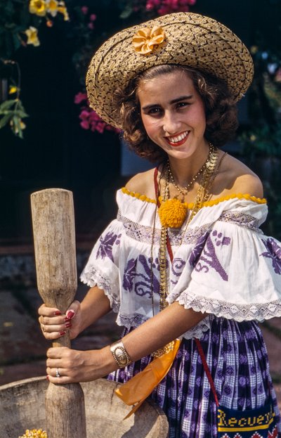 Woman in straw hat of Panama grinding with a traditional mortar and pestle by Luis Marden