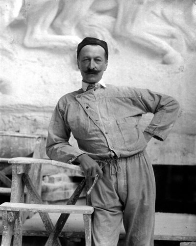 Portrait of the famous sculptor Pietro Canonica in work clothes. The artist is posing in his studio holding a tool of his trade in his right hand by Mario Nunes Vais