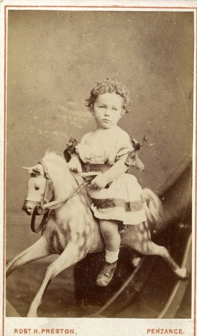 Young girl sitting on a rocking horse by Robert H. Preston