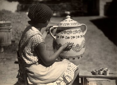 A Hungarian lady painting an amphora with floral motifs by Rudolf Balogh