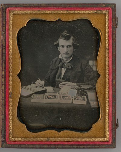 Untitled Portrait of Seated Man Holding a Daguerreotype and Brush by Samuel J. Miller