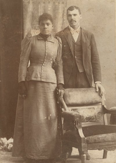 Photograph of an African-American couple standing behind a chair by Schmitz Studio