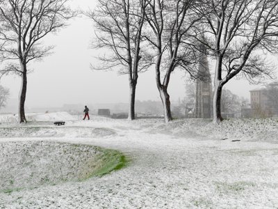 Lone figure walking in Copenhagen Fortress during snowstorm, Denmark, 2022 by Sisse Brimberg