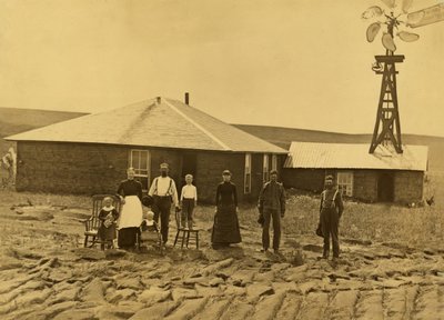 Family of Homesteaders, Outside of Their Sod House with a Windmill on the Roof of the Adjoining Building in Custer County, Nebraska by Solomon D. Butcher