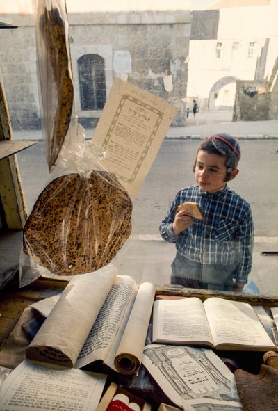 Conservative Jewish boy eating cake peers into a religious bookstore by Ted Spiegel