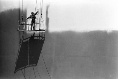 Man on platform painting an oil storage tank by Ted Spiegel