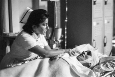 Nurse aids a patient on stretcher after surgery on hospital ship SS Hope by Ted Spiegel