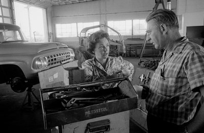 Truck driver Mildred Cooper chats with mechanic in a garage by Ted Spiegel