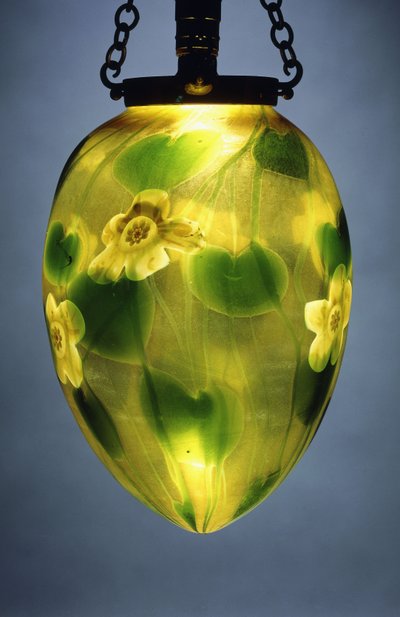 A hanging lantern, decorated with green leaves and vines and yellow iridescent flowers by Tiffany Studios